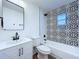 Modern bathroom with white vanity, patterned accent wall, toilet and shower-tub combo at 6602 Winding Brook Dr, New Port Richey, FL 34655