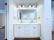 Bathroom featuring double sink vanity, large mirror and brushed nickel lighting at 6602 Winding Brook Dr, New Port Richey, FL 34655