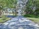 Long driveway leads to a charming home surrounded by lush greenery and mature, moss-covered trees at 6602 Winding Brook Dr, New Port Richey, FL 34655
