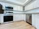 Modern kitchen with stainless steel appliances, white cabinets, and light wood floors at 6602 Winding Brook Dr, New Port Richey, FL 34655
