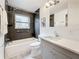 Well lit bathroom features a tub, grey wood-look tile, and stylish vanity with granite countertops at 7125 S Shore S Dr, St Petersburg, FL 33707