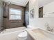Bright bathroom features a bathtub with dark tile surround, a window, and stylish vanity at 7125 S Shore S Dr, St Petersburg, FL 33707