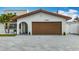 Close-up of the house's front featuring a two-car garage door, brickwork, and manicured landscaping at 7125 S Shore S Dr, St Petersburg, FL 33707