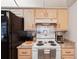 Well-equipped kitchen with a black refrigerator, white stove, and maple cabinets at 953 Tropical Nw Ave, Port Charlotte, FL 33948