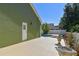Backyard view showcasing a concrete patio, a partial in-ground pool, lush landscaping, and a side door at 9709 Bay Colony Dr, Riverview, FL 33578