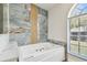Elegant bathroom showcasing a modern soaking tub and a decorative arched window at 9709 Bay Colony Dr, Riverview, FL 33578