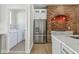 Bright kitchen showcasing stainless steel fridge, brick accent wall, and adjacent laundry room for added convenience at 9709 Bay Colony Dr, Riverview, FL 33578