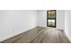 Clean, minimalist bedroom with neutral paint, a window and light colored laminate flooring at 9831 Scenic Dr, Port Richey, FL 34668