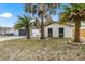 The home's exterior with a well-kept lawn, mature palm trees, and a grey two-car garage at 9831 Scenic Dr, Port Richey, FL 34668
