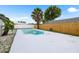 Backyard swimming pool surrounded by a white concrete deck and a wooden fence at 9831 Scenic Dr, Port Richey, FL 34668