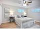 Bright bedroom with light-tone walls, wood floor, ceiling fan and soft, neutral colored bedding at 9929 Bay Dr, Gibsonton, FL 33534