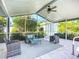 Relaxing screened porch features a ceiling fan, outdoor furniture, and a view of the lush landscaping and detached garage at 9929 Bay Dr, Gibsonton, FL 33534