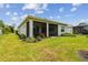 Exterior of the home showing the screened in lanai and lush, green backyard with landscaping at 10036 Beachwalk Dr, Englewood, FL 34223
