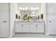 Bathroom with dual sinks, white cabinetry, and expansive mirror at 10036 Beachwalk Dr, Englewood, FL 34223