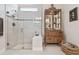 Bathroom with glass shower, neutral tile flooring, and wooden cabinet for storage at 10036 Beachwalk Dr, Englewood, FL 34223