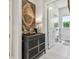 Bright hallway with white tile flooring, a decorative chest, and a view of a window at 10036 Beachwalk Dr, Englewood, FL 34223