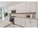Modern kitchen features white cabinetry, stainless steel appliances and a neutral backsplash at 10036 Beachwalk Dr, Englewood, FL 34223