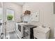 Bright laundry room equipped with modern appliances, a sink, and overhead storage at 10036 Beachwalk Dr, Englewood, FL 34223