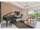 Cozy living room featuring a piano, comfortable seating, and serene view of the outdoor landscape at 10036 Beachwalk Dr, Englewood, FL 34223