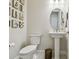 Classic powder room featuring a white pedestal sink, oval mirror, and vintage artwork at 10036 Beachwalk Dr, Englewood, FL 34223