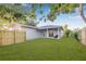 Grey home boasts a well manicured lawn, a wooden fence and covered patio at 1052 55Th N Ave, St Petersburg, FL 33703