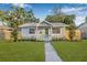 Quaint single-story home features a vibrant green lawn, landscaping and a fresh coat of gray paint at 1052 55Th N Ave, St Petersburg, FL 33703