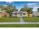 Charming single-story home with a well-manicured lawn, mature trees and a tidy walkway to the front door at 1052 55Th N Ave, St Petersburg, FL 33703