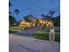 Stunning home at dusk featuring lush landscaping, elegant lighting, and a paver driveway at 10532 Cory Lake Dr, Tampa, FL 33647