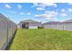 Large backyard with green lawn, bordered by a white fence, and patio in view at 10945 High Noon Trl, Parrish, FL 34219