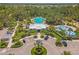 Aerial view of the community pool featuring palm trees, splashpad and lounge chairs surrounded by lush greenery at 10945 High Noon Trl, Parrish, FL 34219