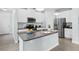 Modern kitchen with stainless steel appliances, granite countertops, and a central island with bar seating at 10945 High Noon Trl, Parrish, FL 34219