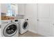 Bright laundry room with white washer and dryer, storage cabinets, and a window for natural light at 10945 High Noon Trl, Parrish, FL 34219