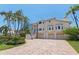Elegant home featuring a brick driveway, three-car garage, and landscaped front yard with tropical trees at 1156 2Nd S Ave, Tierra Verde, FL 33715