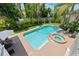 Aerial view of a refreshing pool and jacuzzi surrounded by tropical landscaping with lounge seating at 1156 2Nd S Ave, Tierra Verde, FL 33715
