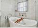 A bright bathroom featuring a soaking tub with a wooden tray and stylish fixtures at 11602 Sunburst Marble Rd, Riverview, FL 33579