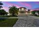 Charming exterior with paver driveway, three-car garage and well-maintained landscaping at dusk at 11602 Sunburst Marble Rd, Riverview, FL 33579