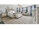 Cozy main bedroom features a tufted bed, sitting area, neutral color palette, and ample natural light from the large windows at 11602 Sunburst Marble Rd, Riverview, FL 33579