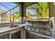 Outdoor kitchen with sink, grill, and ample storage space within a screened-in patio at 11602 Sunburst Marble Rd, Riverview, FL 33579