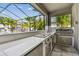 Outdoor kitchen featuring a large countertop, grill, and ample storage space in a screened patio at 11602 Sunburst Marble Rd, Riverview, FL 33579