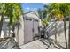 Durable shed with a neutral color scheme, blending seamlessly into the landscape, complemented by lush palm trees at 11602 Sunburst Marble Rd, Riverview, FL 33579