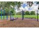 Community exercise area with blue exercise equipment set on wood chips with lush green grass and shade trees at 11641 Branch Mooring Dr, Tampa, FL 33635
