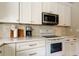 Kitchen featuring white cabinets, tile backsplash, and stainless steel microwave at 11641 Branch Mooring Dr, Tampa, FL 33635