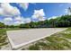 Community sand volleyball court with blue net, surrounded by lush grass and trees on a sunny day with blue skies at 11641 Branch Mooring Dr, Tampa, FL 33635