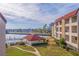 Exterior view features a body of water, palm trees, manicured lawn, and condominium buildings at 120 1St E St # 109, Tierra Verde, FL 33715