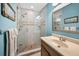 Bathroom featuring a glass shower with beige tile, blue walls and a granite topped vanity at 13303 Gulf Ln, Madeira Beach, FL 33708