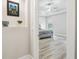 View of a bedroom with light wood flooring and a ceiling fan; artwork decorates the hallway entrance at 13334 Oldenburg Dr, Hudson, FL 34667
