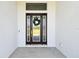Elegant front door with glass panels and a decorative wreath, offering a warm welcome at 13334 Oldenburg Dr, Hudson, FL 34667