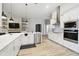 Spacious open kitchen featuring stainless steel appliances, white cabinetry, and wood look flooring at 13334 Oldenburg Dr, Hudson, FL 34667