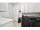 Functional laundry room with black washer and dryer units, and ample white storage cabinets at 13334 Oldenburg Dr, Hudson, FL 34667