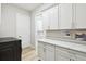 Well-organized laundry room with white cabinets, countertops, and a door leading to an adjacent room at 13334 Oldenburg Dr, Hudson, FL 34667